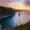 green and brown mountain beside body of water during sunset